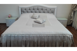 Общий вид кровати с покрывалом и подушками украшенными бахромой.