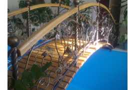 Мостик через бассейн из металла и дерева с элементами виноградной лозы.