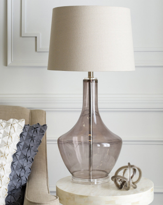 Настольная лампа с основанием из дутого серого стекла и белым абажуром.