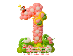 Цифра 1 из розовых и белых шаров с бабочкой и букашкой, расположенной на зеленой полянке