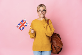 девушка в желтом свитере и очках стоит с британским флагом в руке