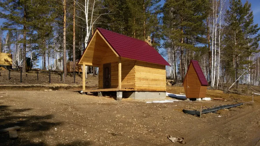 На срубе собрана стропильная система, произведен монтаж металлочерепицы, установлена металлическая дверь.
Рядом с баней установлена уборная, кровля металлочерепица, фасады евро вагонка обработанная деревозащитным составом.