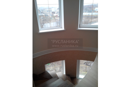 Лестница со второго этажа идёт с вдоль округлой  стены с окнами.