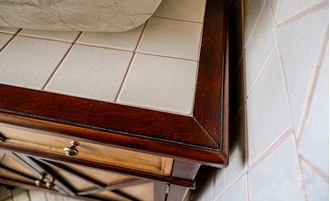 Тумба под раковину со столешницей из плитки с деревянным краем.