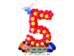 Красная плетеная цифра 5 из шаров на полянке, декорирована вертолетом и машинками