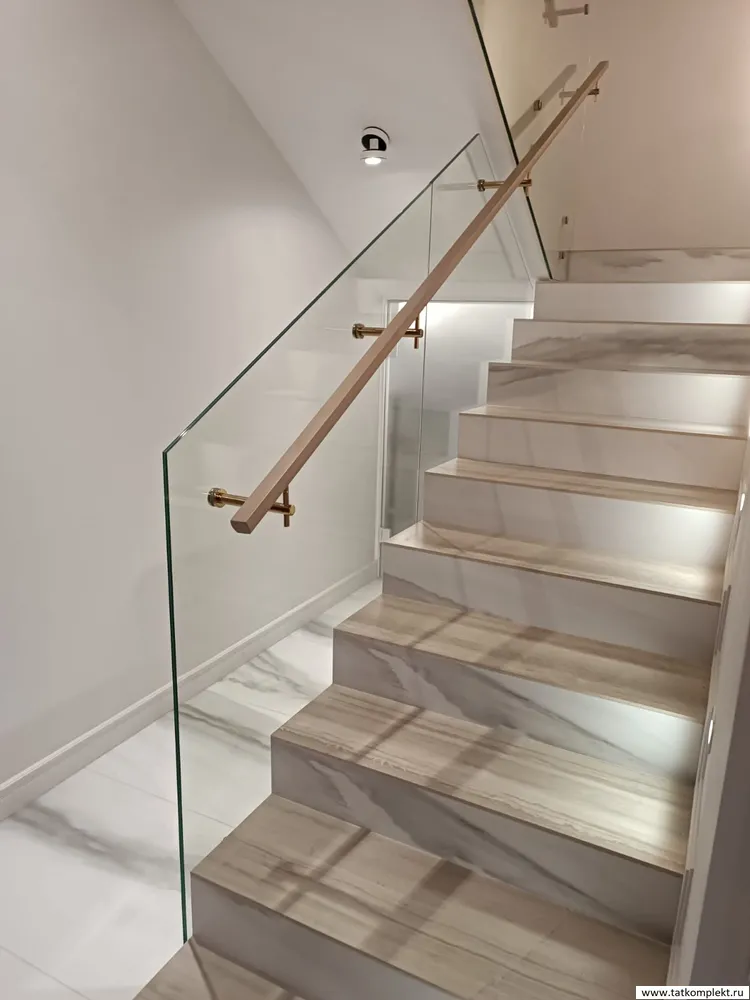 Стеклянное ограждение лестницы с фурнитурой под золото с покрытием нитрит титана. Поручень деревянный - бук. Стекло крепится на точечные   стеклодержатели. 