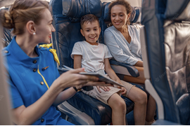 стюардесса показывает в самолете ребенку книгу, ребенок улыбается