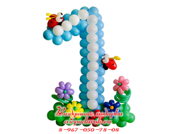 Цифра из голубых и белых шариков, стоящая на зеленой полянке