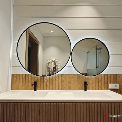 Круглое зеркало в черной рамке с интерьерной подсветкой.