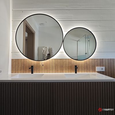 Круглое зеркало в черной рамке с интерьерной подсветкой.