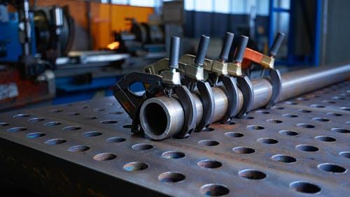 Поверхность стального сварочного стола крупным планом с координатной сеткой и отверстиями для фиксат