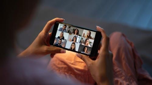 Экран смартфона в руках человека, показывающий группу поддерживающих людей.