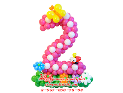 Розовая цифра 2 с белыми вставками из шаров, стоящая на зеленой полянке