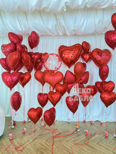 Праздничное оформление интерьера спальни множеством красных гелиевых шаров в форме сердец Троицк Нов