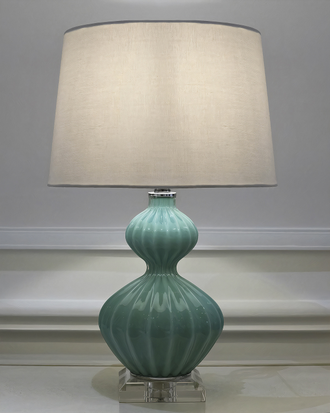 Настольная лампа c бирюзовым основанием и белым абажуром.