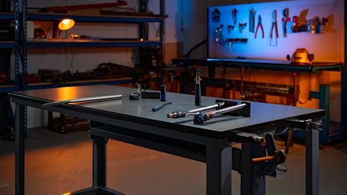 Организованное рабочее место сварщика в цеху с массивным столом и инструментами на заднем плане.