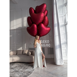 Девушка в длинном белом платье на фоне панорамного окна с огромным облаком винно-красных гелиевых се