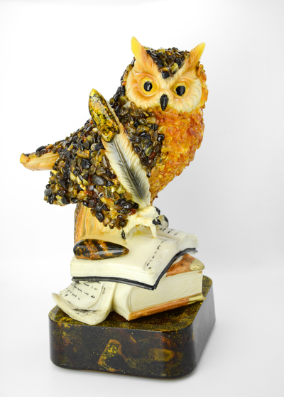Сова с пером на книгах на подставке