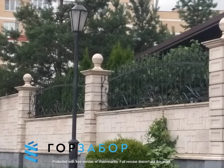 Установка забора с элементами ковки между бетонными столбами