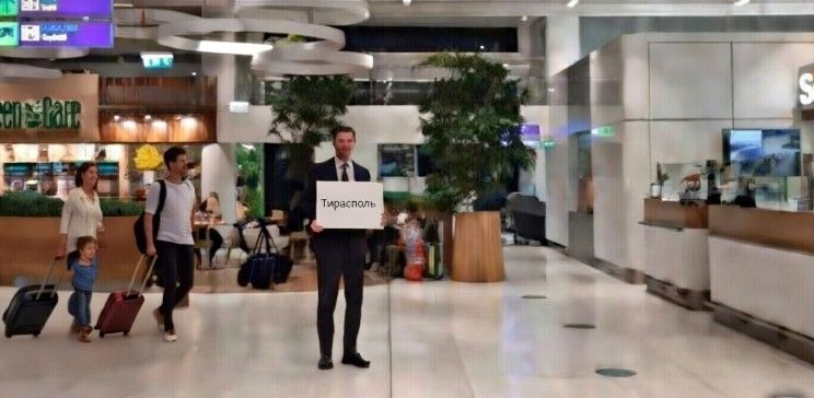 Водитель такси с табличкой в зале прилёта аэропорта RMO