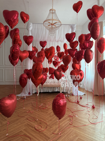 Праздничное оформление интерьера спальни множеством красных гелиевых шаров в форме сердец Троицк Нов