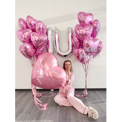 евушка с огромным розовым сердцем и фонтанами из шаров на фоне серебряных букв I U в Троицке