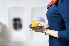 стюардесса несет апельсиновый сок пассажиру самолета