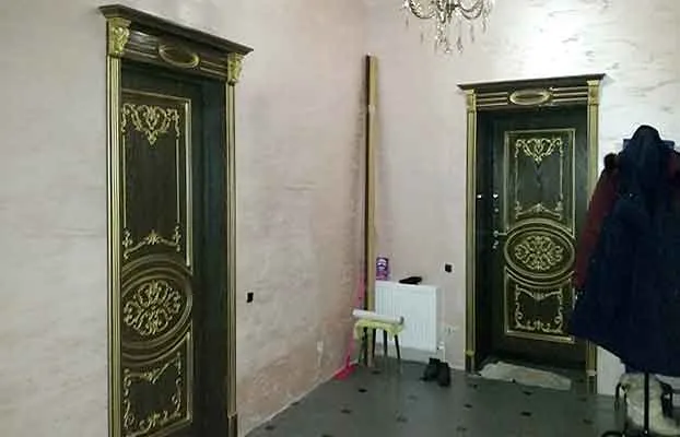 Отделка дверных проемов на первом этаже дома. Входная дверь в дом  изготовлена на заказ с внутренней панелью  под межкомнатные.В отделке откосов применены доборы шириной 40 см и капитель №7 с патиной.