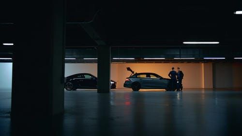 Два премиальных автомобиля на подземном паркинге и бизнесмены за беседой