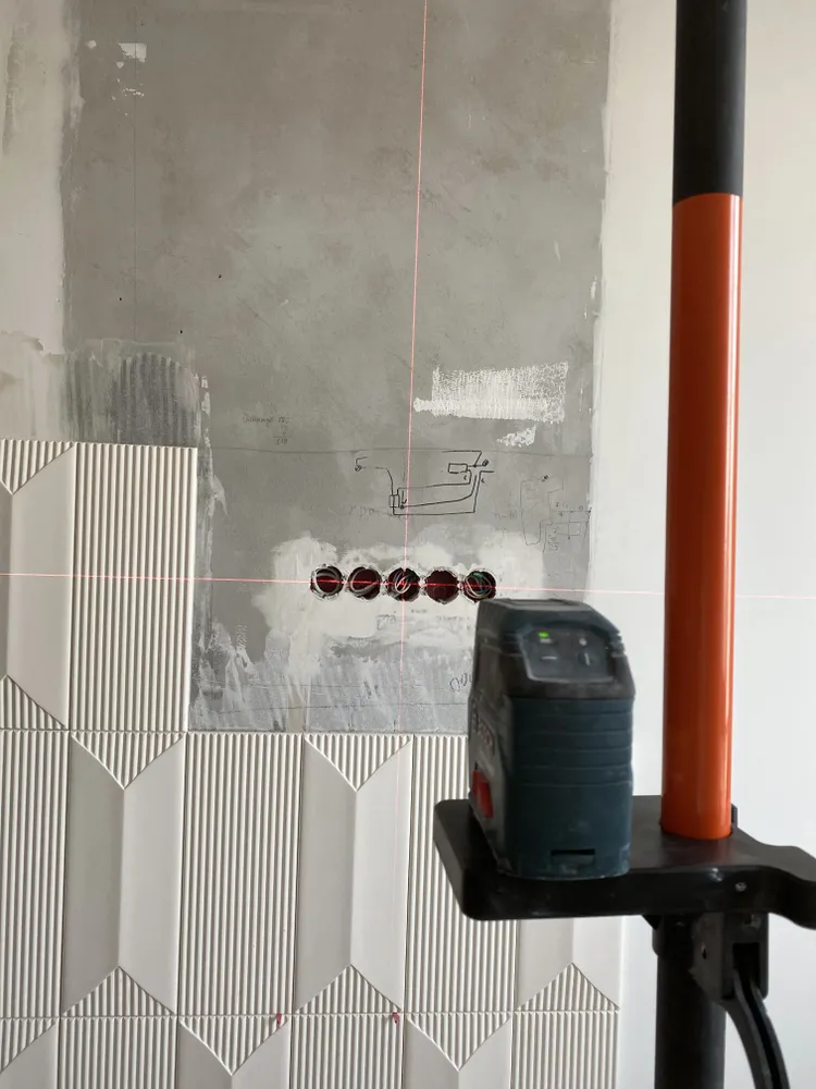 Совмещаем лучи лазера с центром розеток. Переносим метки на уже смонтированные панели и за края композиции. Смело закрываем розетки панелями.