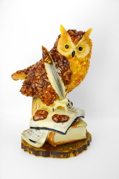 Сова с пером на книгах на подставке