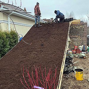 Наклонная крыша засыпана субстратом для кровельного озеленения, под ним георешетка и дренаж