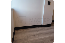 Изысканная отделка помещения: установка черного алюминиевого плинтуса ПЛ 100 с роскошным муаровым покрытием.