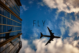 самолет летит на фоне неба и здания