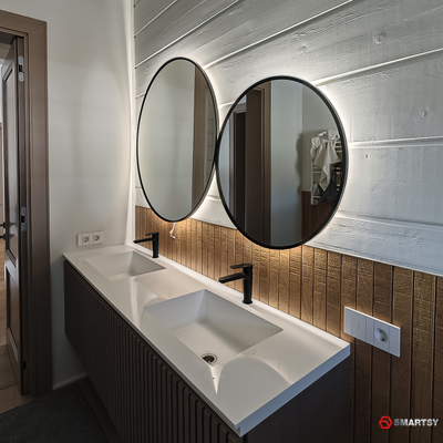 Круглое зеркало в черной рамке с интерьерной подсветкой.