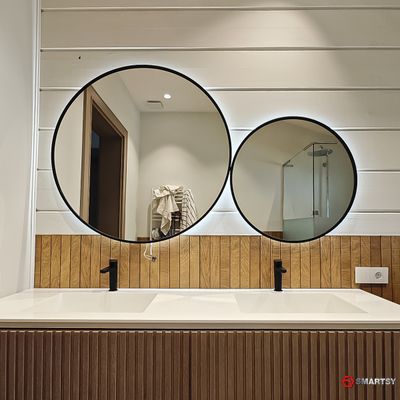 Круглое зеркало в черной рамке с интерьерной подсветкой.